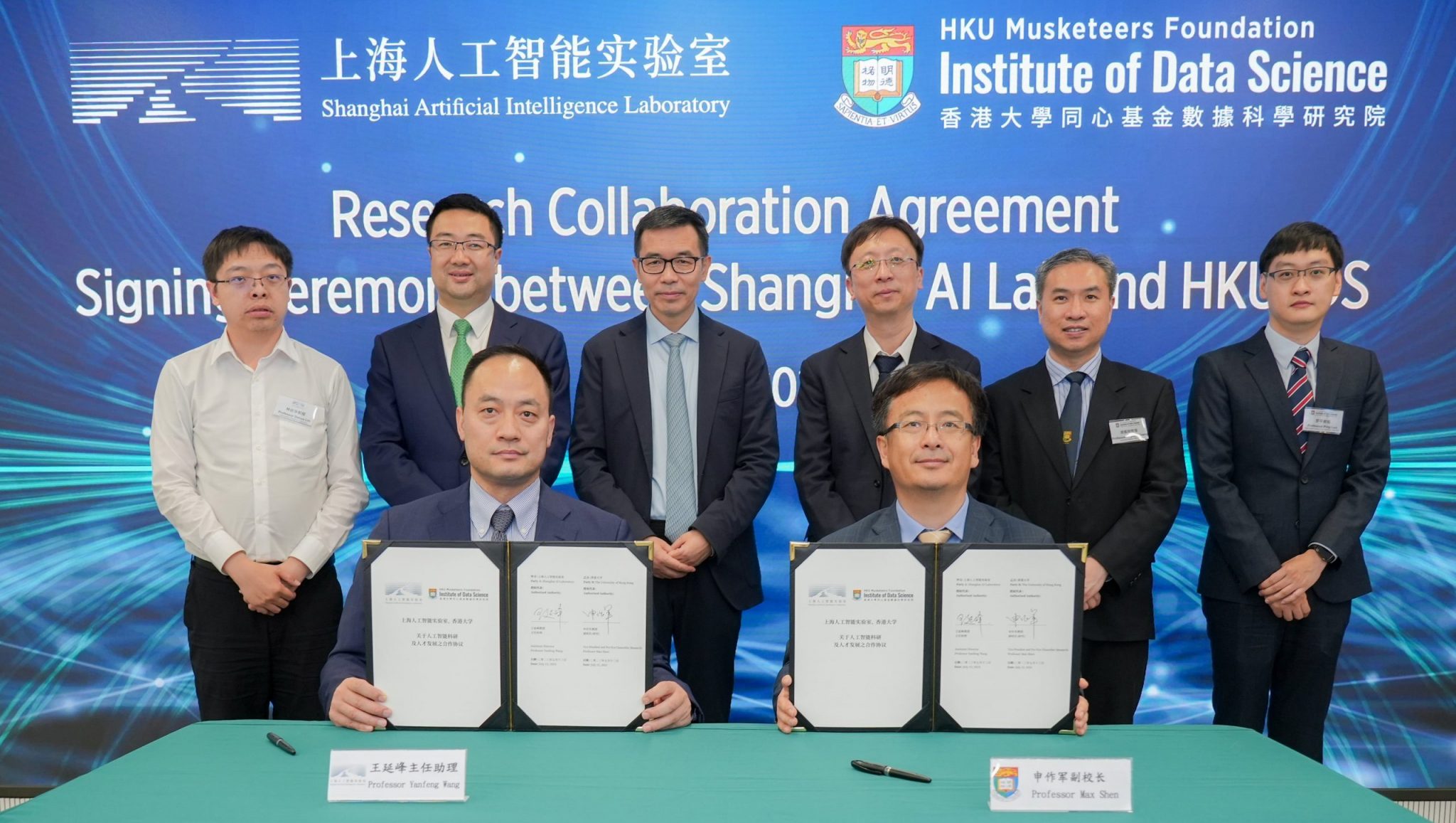 A group of eight professional individuals, including two seated at a table holding signed documents, participate in a formal research collaboration agreement ceremony between Shanghai Artificial Intelligence Laboratory and HKU Institute of Data Science, with a large blue backdrop displaying logos and bilingual text highlighting AI, education, and university innovation initiatives.